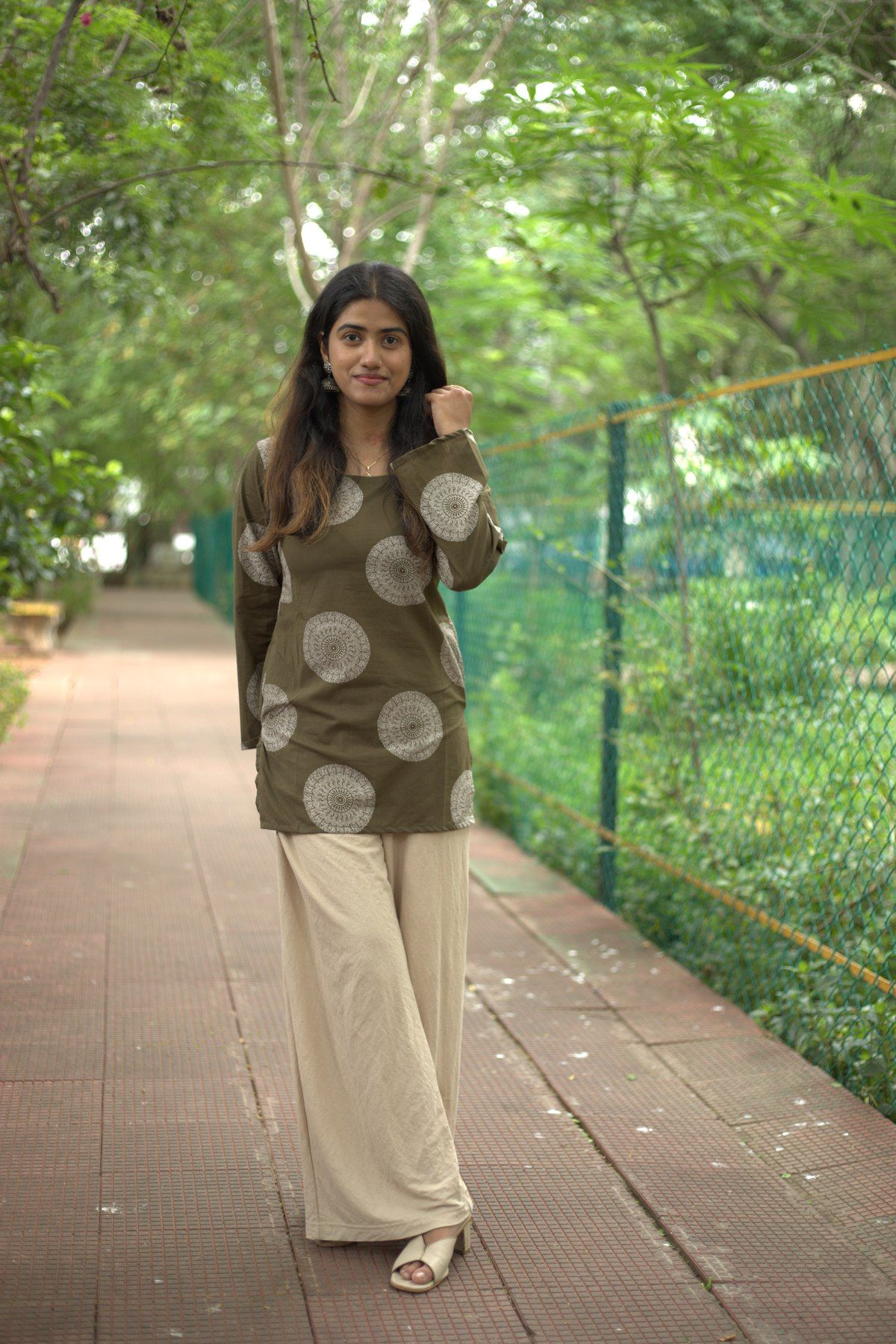 Full-length view of the olive mandala top worn with cream palazzo